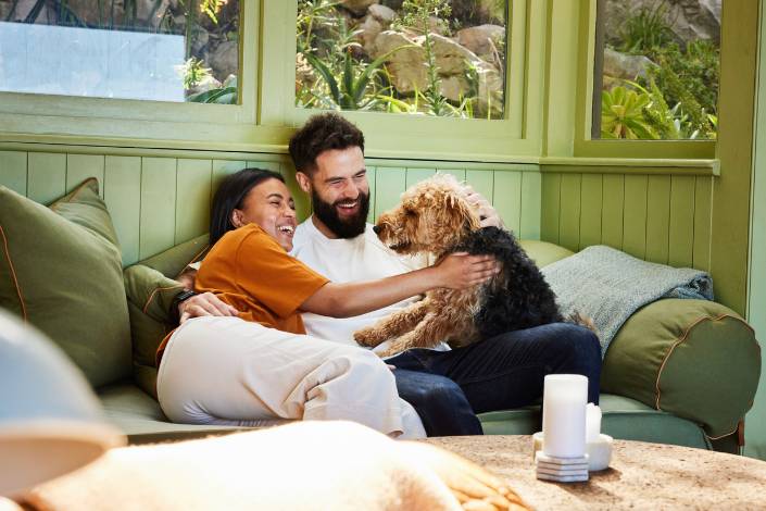two house sitters sitting on couch with dog